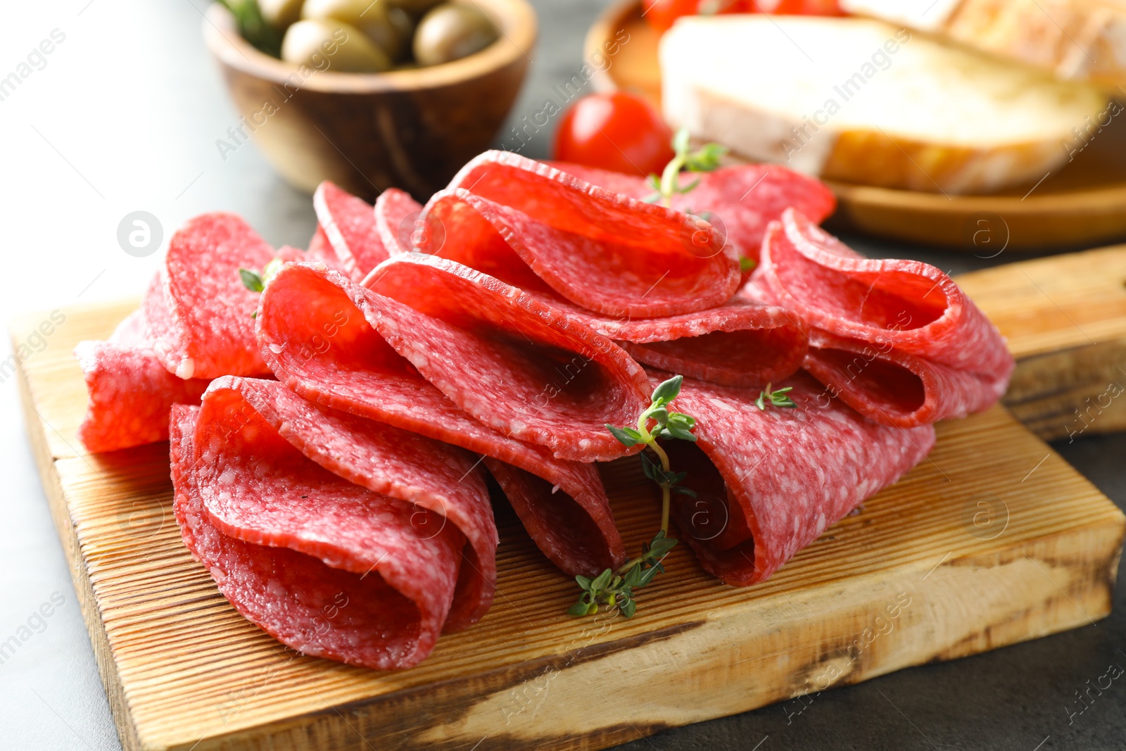 Slices of delicious sausage with thyme served on grey table, closeup Photo of Slices of delicious sausage with thyme served on grey table, closeup