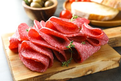 Photo of Slices of delicious sausage with thyme served on grey table, closeup