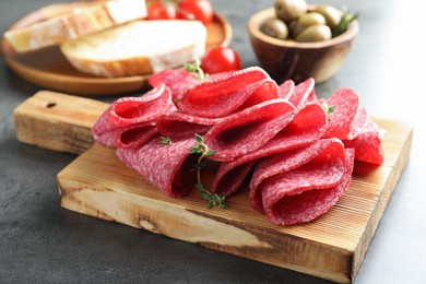 Photo of Slices of delicious sausage with thyme served on grey table, closeup