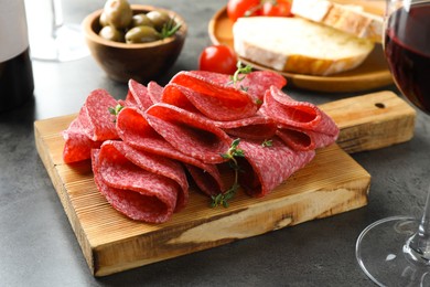 Photo of Slices of delicious sausage with thyme served on grey table, closeup