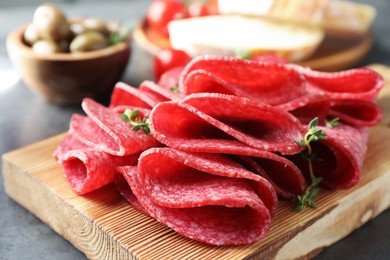 Photo of Slices of delicious sausage with thyme served on grey table, closeup