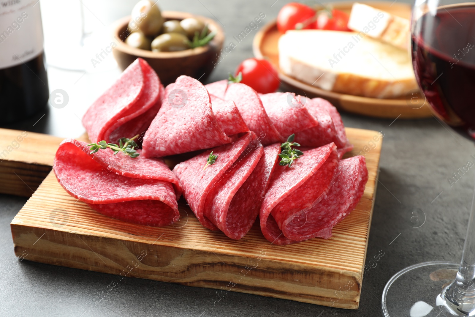Slices of delicious sausage with thyme served on grey table, closeup Photo of Slices of delicious sausage with thyme served on grey table, closeup