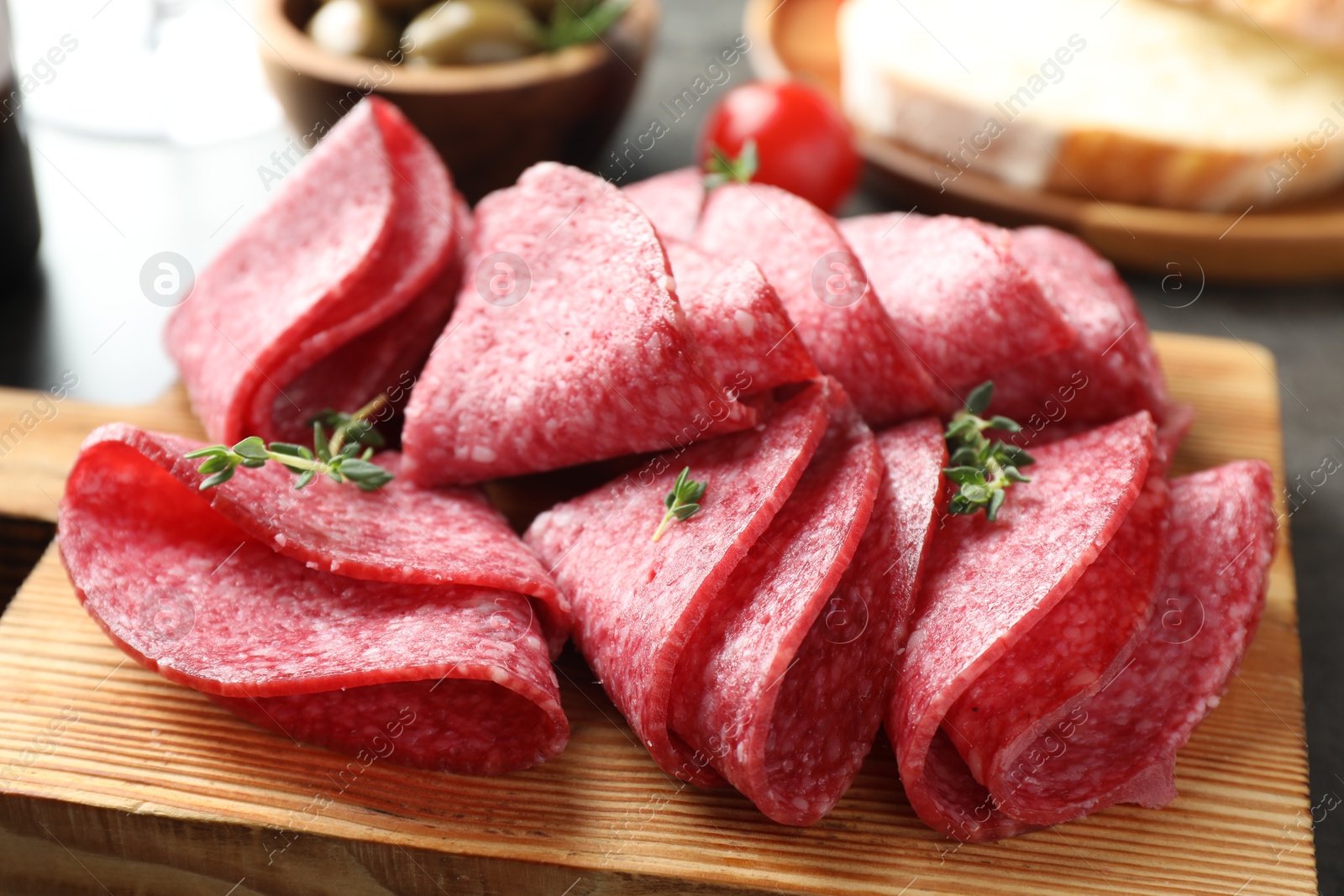 Slices of delicious sausage with thyme served on grey table, closeup Photo of Slices of delicious sausage with thyme served on grey table, closeup