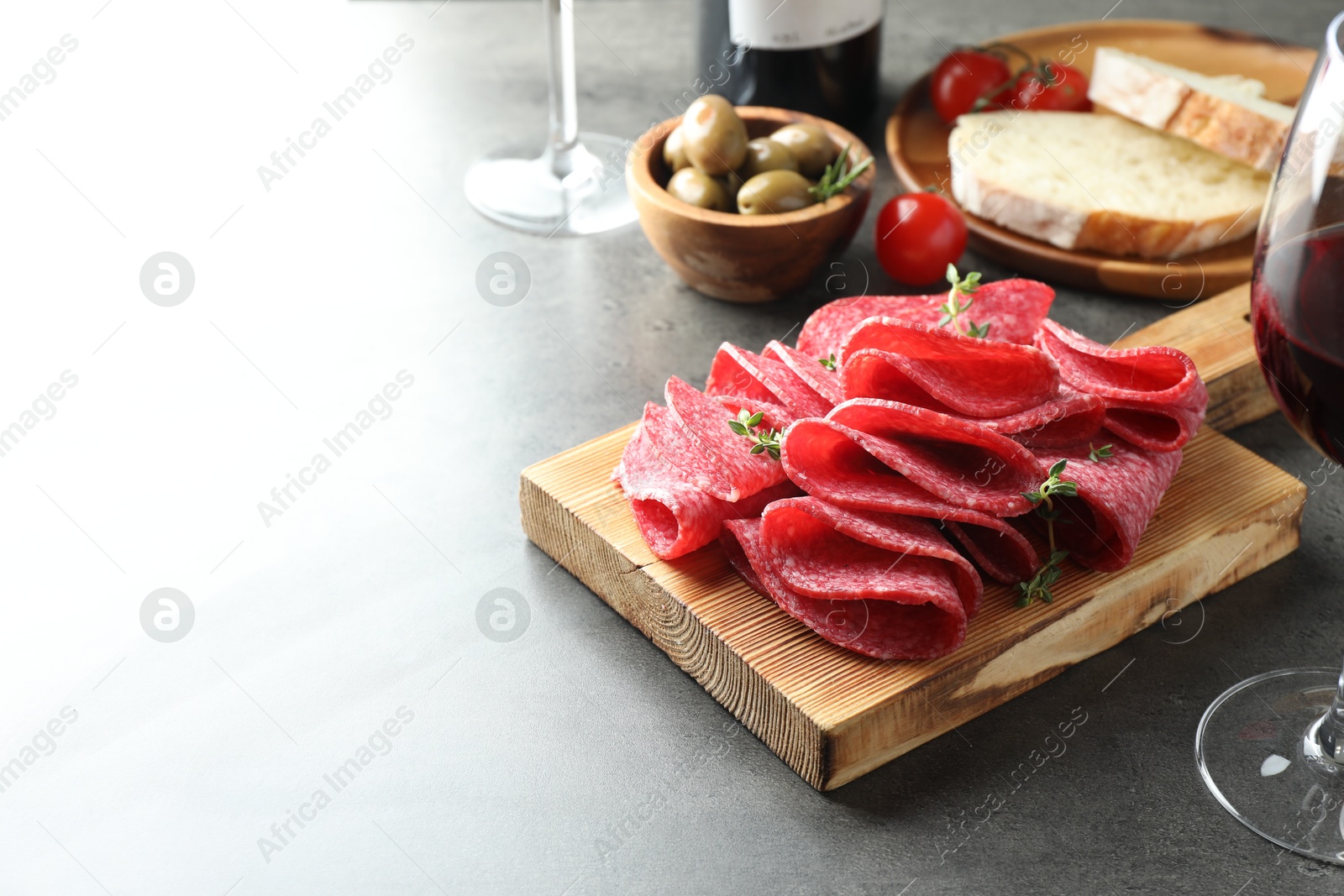 Slices of delicious sausage with thyme served on grey table. Space for text Photo of Slices of delicious sausage with thyme served on grey table. Space for text