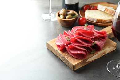Photo of Slices of delicious sausage with thyme served on grey table. Space for text