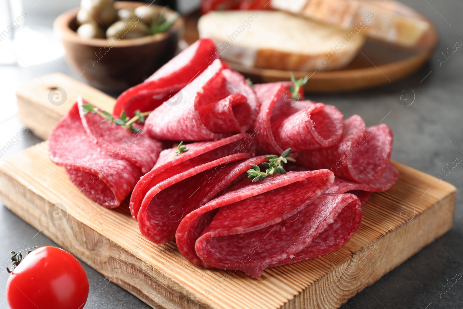 Photo of Slices of delicious sausage with thyme served on grey table, closeup