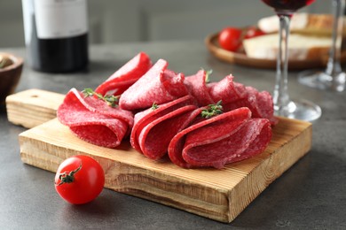 Photo of Slices of delicious sausage with thyme served on grey table, closeup