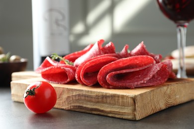 Photo of Slices of delicious sausage with thyme served on grey table, closeup