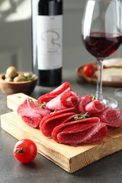 Photo of Slices of delicious sausage with thyme served on grey table, closeup