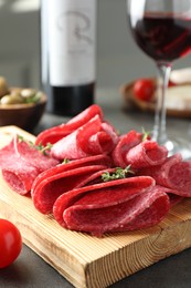 Photo of Slices of delicious sausage with thyme served on grey table, closeup
