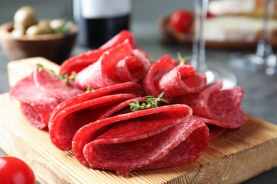 Photo of Slices of delicious sausage with thyme served on table, closeup