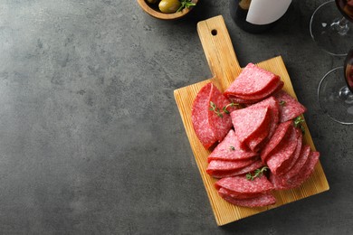 Photo of Slices of delicious sausage with thyme served on grey table, flat lay. Space for text