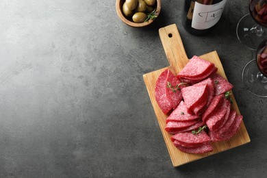 Photo of Slices of delicious sausage with thyme served on grey table, flat lay. Space for text