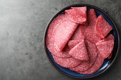 Photo of Slices of delicious sausage served on grey table, top view. Space for text