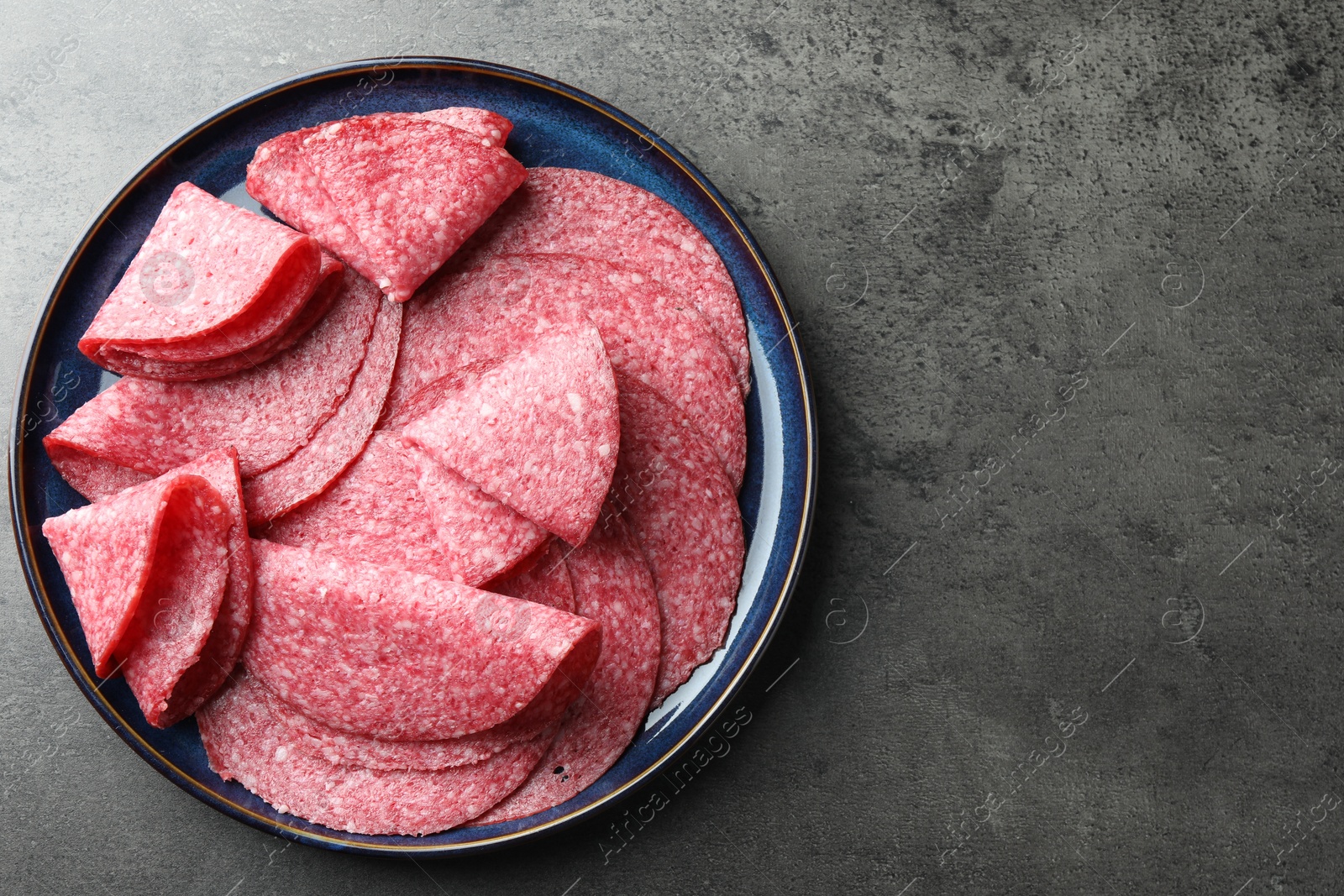 Slices of delicious sausage served on grey table, top view. Space for text Photo of Slices of delicious sausage served on grey table, top view. Space for text