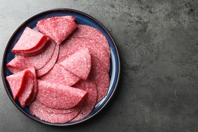 Photo of Slices of delicious sausage served on grey table, top view. Space for text