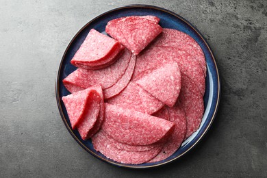 Photo of Slices of delicious sausage served on grey table, top view