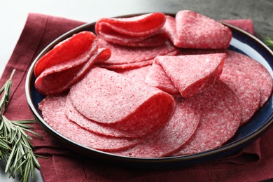 Photo of Slices of delicious sausage served on grey table, closeup