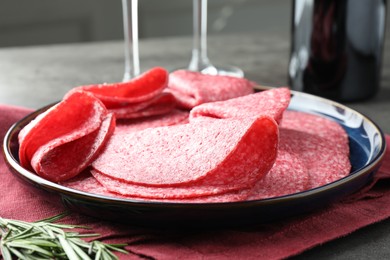 Photo of Slices of delicious sausage served on grey table, closeup
