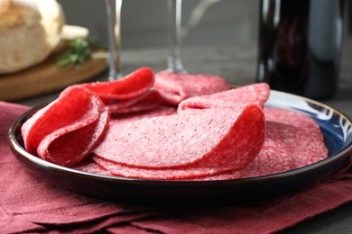 Photo of Slices of delicious sausage served on grey table, closeup