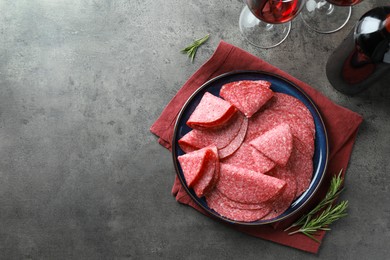 Photo of Slices of delicious sausage served on grey table, flat lay. Space for text