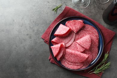 Photo of Slices of delicious sausage served on grey table, flat lay. Space for text