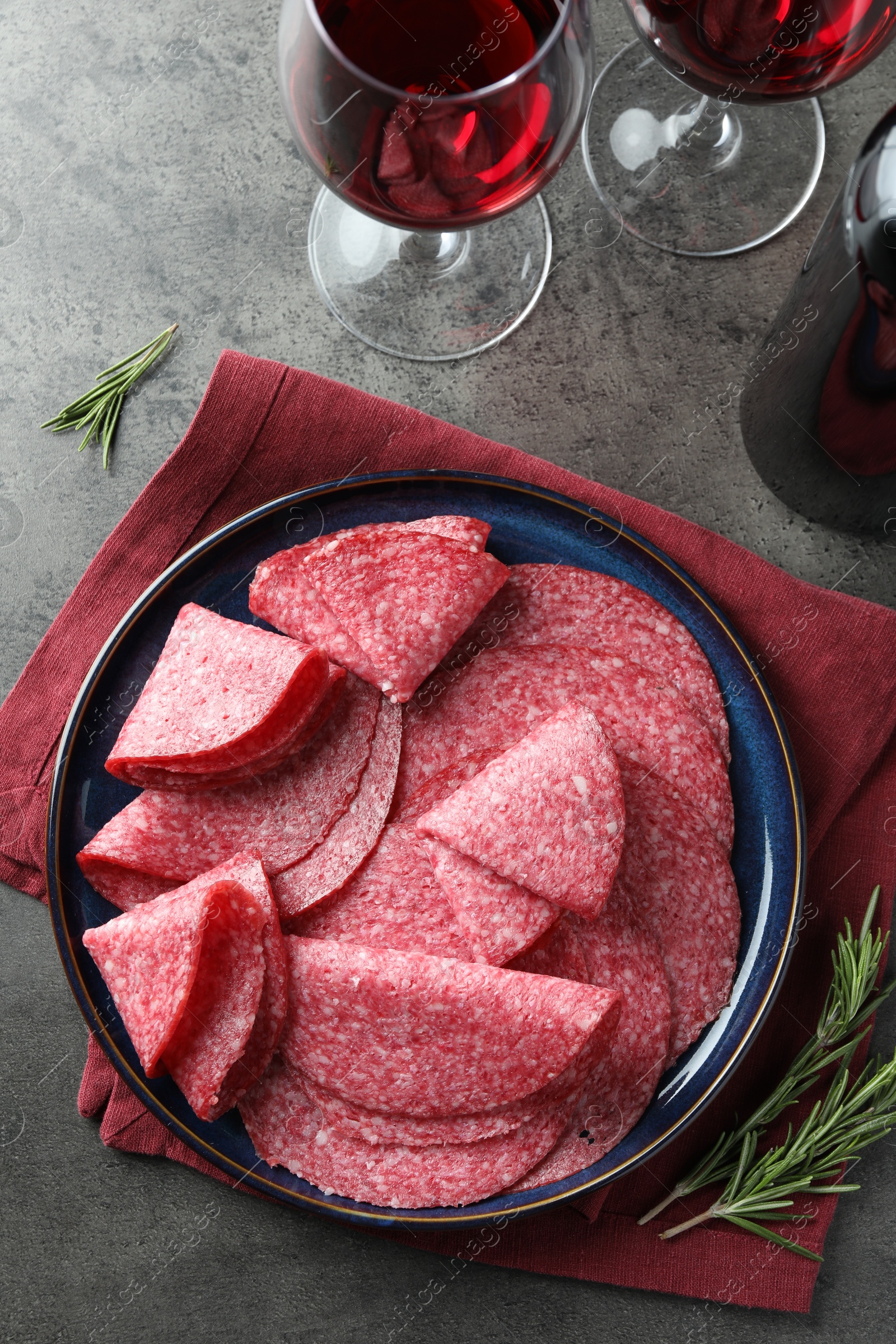 Photo of Slices of delicious sausage served on grey table, flat lay