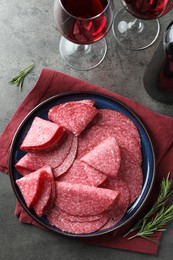 Photo of Slices of delicious sausage served on grey table, flat lay