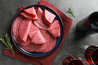 Photo of Slices of delicious sausage served on grey table, flat lay