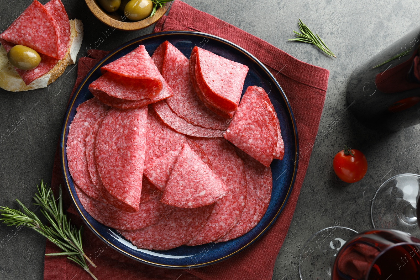 Slices of delicious sausage served on grey table, flat lay Photo of Slices of delicious sausage served on grey table, flat lay
