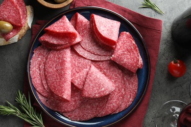 Photo of Slices of delicious sausage served on grey table, flat lay