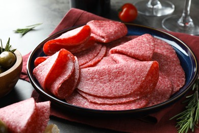 Photo of Slices of delicious sausage served on grey table, closeup