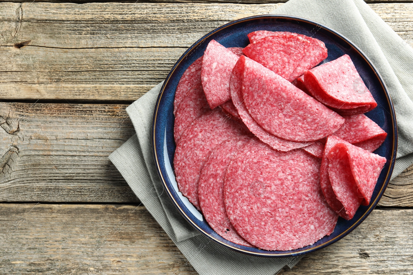 Slices of delicious sausage on wooden table, top view Photo of Slices of delicious sausage on wooden table, top view