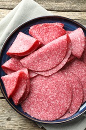 Photo of Slices of delicious sausage on wooden table, top view