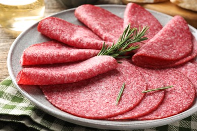 Photo of Slices of delicious sausage with rosemary served on table, closeup