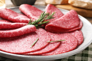 Photo of Slices of delicious sausage with rosemary served on table, closeup