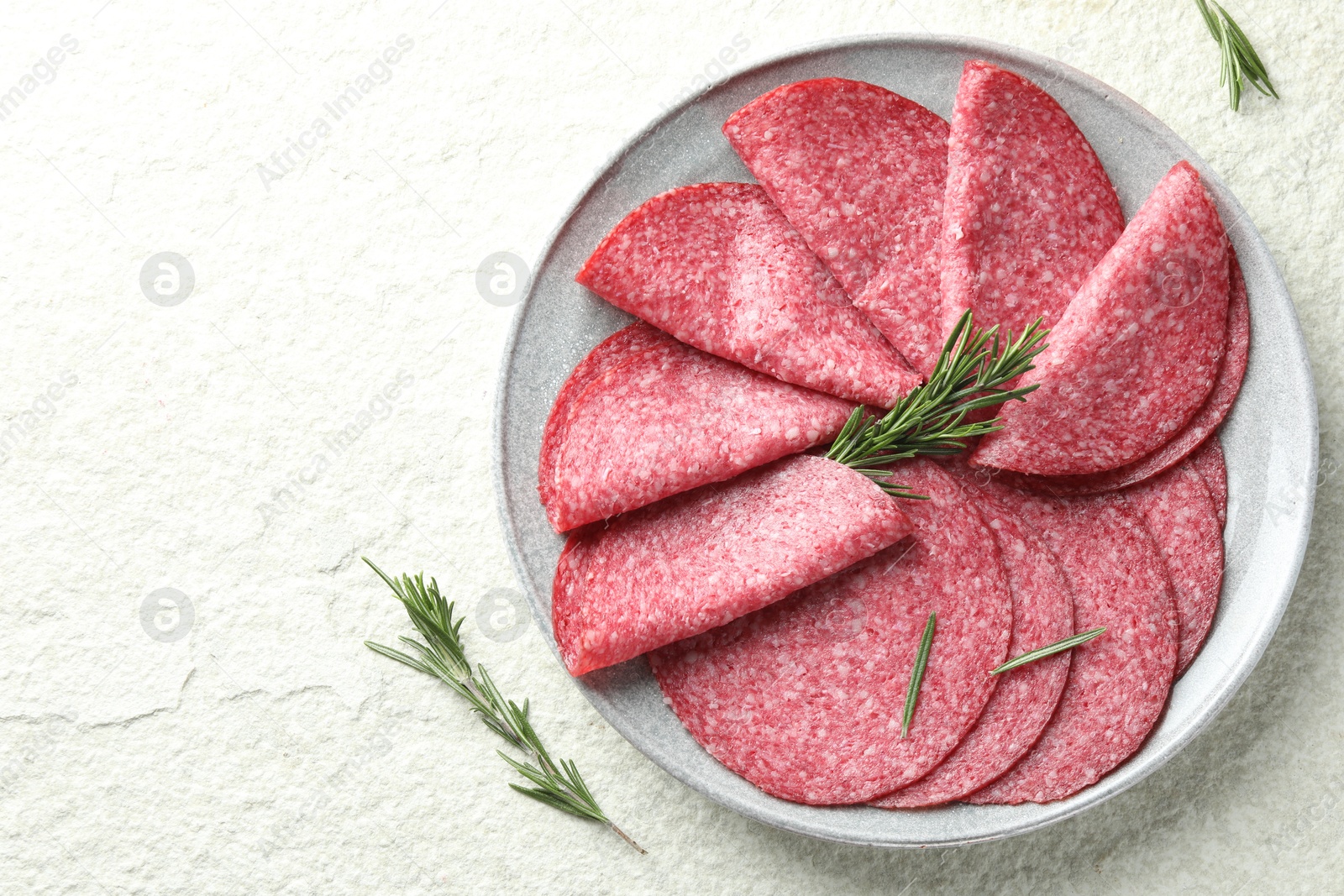Slices of delicious sausage with rosemary served on white textured table, top view. Space for text Photo of Slices of delicious sausage with rosemary served on white textured table, top view. Space for text
