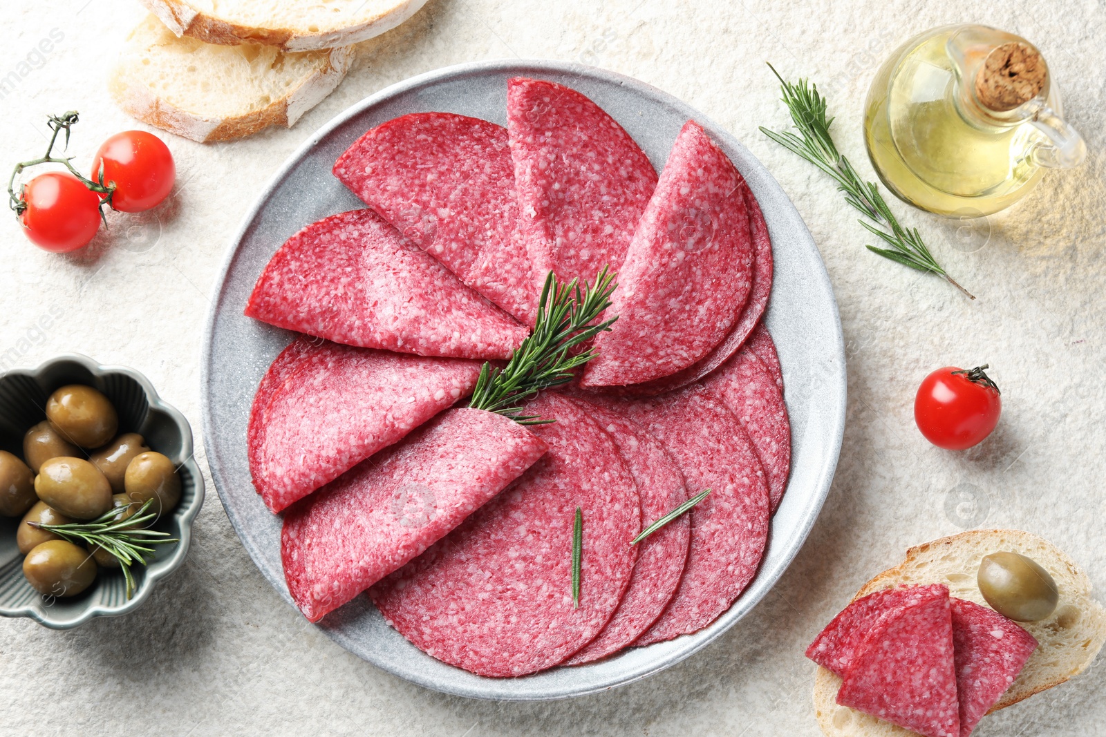 Slices of delicious sausage with rosemary served on white textured table, flat lay Photo of Slices of delicious sausage with rosemary served on white textured table, flat lay