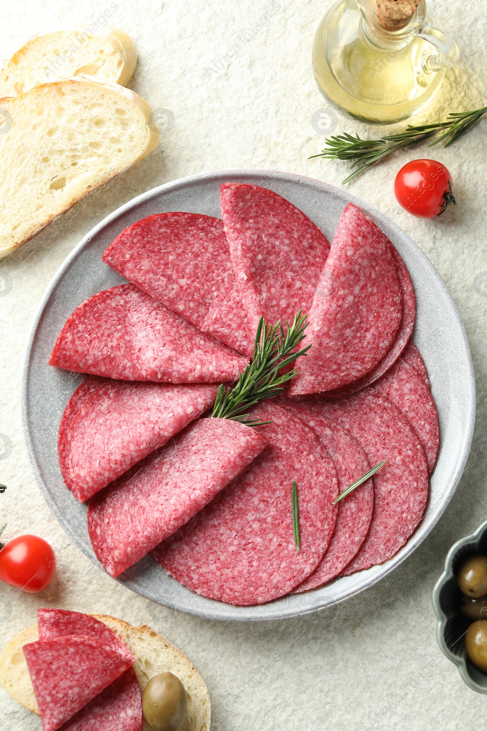 Slices of delicious sausage with rosemary served on white textured table, flat lay Photo of Slices of delicious sausage with rosemary served on white textured table, flat lay
