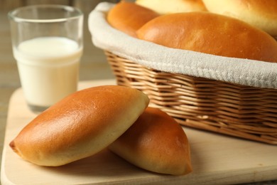 Photo of Tasty baked patties and milk on wooden table, closeup