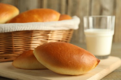 Photo of Tasty baked patties and milk on wooden table, closeup