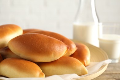 Photo of Tasty baked patties and milk on wooden table, closeup
