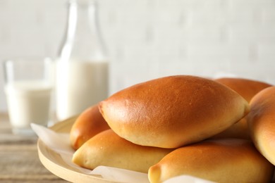 Photo of Tasty baked patties and milk on wooden table, closeup. Space for text
