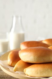 Photo of Tasty baked patties and milk on wooden table, closeup. Space for text