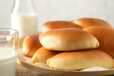 Photo of Tasty baked patties and milk on wooden table, closeup