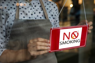 Image of Woman hanging No Smoking sign in cafe, closeup. View from outdoors