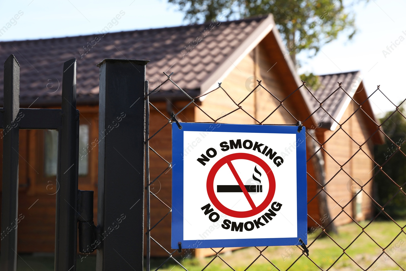 Image of No Smoking sign on fence outdoors. Prohibition