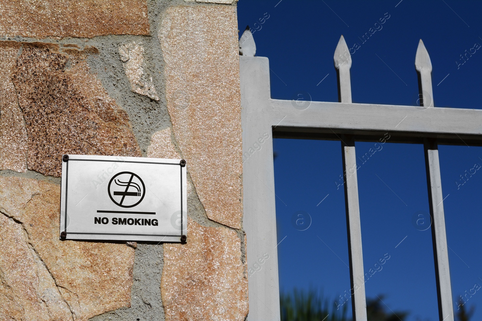 Image of No Smoking sign on fence outdoors. Prohibition