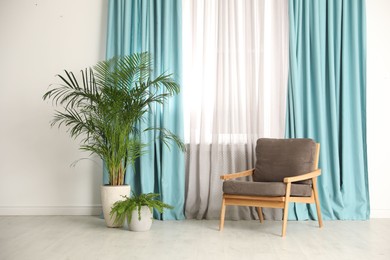 Photo of Comfortable armchair near window with elegant curtains in room