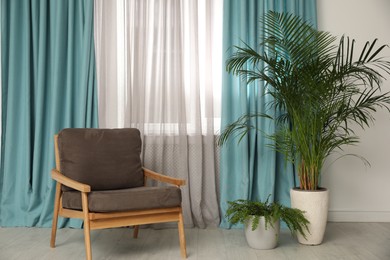 Photo of Comfortable armchair near window with elegant curtains in room